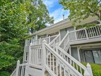 Charming two-story condo with light gray siding and white trim, nestled among lush greenery under a bright blue sky at 212 Abingdon Way, Atlanta, GA 30328