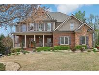 Charming two-story home with a brick and stone facade, covered porch, manicured lawn, and professional landscaping at 1870 Marcia Overlook Dr, Cumming, GA 30041