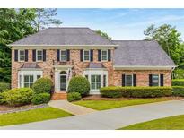 Elegant brick home with symmetrical design, manicured landscaping, and a curved driveway at 360 Spindle Ct, Sandy Springs, GA 30350