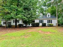 Charming single-story home with dormer windows and a lush, wooded front yard at 1905 Sidneys Cv, Lawrenceville, GA 30043