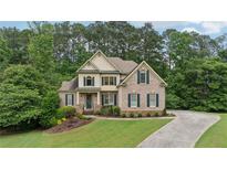 Beautiful brick home with manicured lawn and lush landscaping, set amongst mature trees at 223 Falling Water Way, Woodstock, GA 30188