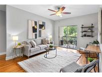 Bright living room with a ceiling fan, modern art, and a sliding glass door to the outdoor patio at 1075 Peachtree Walk # A-307, Atlanta, GA 30309