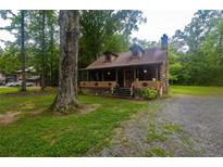 Charming log cabin with a stone chimney, dormer windows, and a cozy front porch at 218 Green Acre Ln, Cartersville, GA 30121