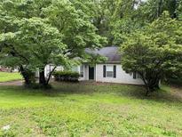 Quaint one-story home with green lawn and mature trees offering shade and privacy at 425 Rockingham Ln, Woodstock, GA 30189