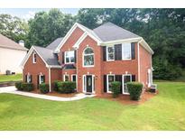 Charming two-story red brick home featuring black shutters and a well-manicured front lawn at 3932 E Saddle Ridge Dr, Lithonia, GA 30038