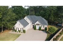 Stunning two-story brick home featuring a well-manicured lawn, a circular driveway, and lush, mature landscaping at 255 Carriage Station Dr, Lawrenceville, GA 30046