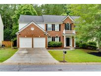 Charming two-story brick home featuring an attached two-car garage and manicured front lawn at 118 Brendylynn Trce, Woodstock, GA 30188