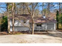 Charming split-level home featuring a metal roof and a cozy front porch at 7000 Woodland Nw Pl, Kennesaw, GA 30152