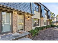 Charming townhome featuring brick facade and dark trim windows, complemented by lush green landscaping at 162 Lablanc Nw Way, Atlanta, GA 30327