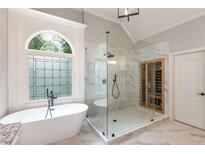 Bright bathroom with a stand alone tub next to a stained glass window and walk-in glass shower with a sauna in the corner at 5173 Brendlynn Dr, Suwanee, GA 30024