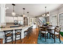 Spacious white kitchen featuring a large island with counter seating and a breakfast nook with a round table at 5173 Brendlynn Dr, Suwanee, GA 30024