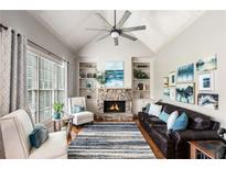 Cozy living room with a stone fireplace, vaulted ceiling, and plush seating arrangement at 5173 Brendlynn Dr, Suwanee, GA 30024