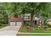 Charming brick home featuring a well-manicured lawn and a two-car garage at 107 W Point Trl, Woodstock, GA 30189