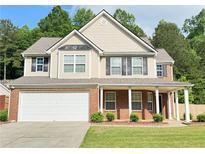 Charming two-story home with a brick and vinyl exterior, a two-car garage, and a welcoming front porch at 5421 Skylar Creek Ln, Buford, GA 30518