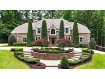Elegant brick home with meticulously landscaped front yard, mature trees, and circular driveway at 4995 Aviary Nw Dr, Acworth, GA 30101
