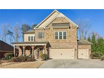 Charming two-story home with a stone and brick facade, complemented by a well-manicured lawn and inviting covered porch at 5365 Vendelay Ln, Cumming, GA 30040