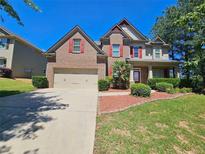 Charming two-story brick home with a well-manicured lawn and two-car garage at 1021 Rock Elm Dr, Auburn, GA 30011