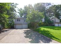 Split-level home featuring a front yard and a two-car garage nestled within a lush, green surrounding at 1112 Mountain Springs Nw Dr, Kennesaw, GA 30144