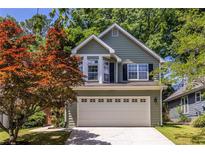 Charming two-story home with a well-maintained lawn and a two car garage and colorful tree at 1100 Ashbury Dr, Decatur, GA 30030
