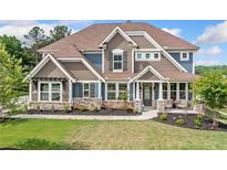 Charming two-story home with a beautiful landscaped yard, stone accents, and a welcoming front porch at 2121 Harmony Dr, Canton, GA 30115