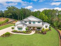 Stunning two-story white home with black trim, a covered porch, lush landscaping, and a long driveway on a large lot at 6301 New Bethany Rd, Buford, GA 30518