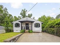 Charming home featuring a manicured lawn, stylish black shutters, and a welcoming covered front porch at 1268 Ladd Sw St, Atlanta, GA 30310