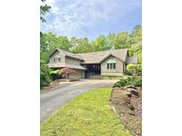 Charming home exterior featuring lush landscaping and a curved driveway at 1678 Rabke Rd, Canton, GA 30114