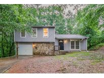 Charming home featuring a stone accent wall, garage, and nestled among mature trees at 4905 Sandberg Ct, Stone Mountain, GA 30088