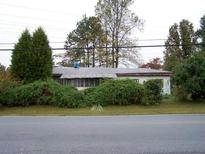Modest single-story home with mature landscaping and a screened-in porch, offering curb appeal and outdoor living space at 688 Collinsworth Rd, Palmetto, GA 30268