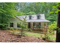 Charming cottage-style home featuring a metal roof and a covered front porch, nestled among mature trees at 345 Jesse Martin Trl, Canton, GA 30115