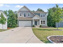 Charming two-story home featuring a two-car garage, landscaped yard, and modern architectural details at 6065 Crescent Landing Dr, Cumming, GA 30028
