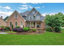 Inviting two-story home with a brick facade, manicured landscaping, and lush green lawn on a sunny day at 26 Trillium Ln, Acworth, GA 30101