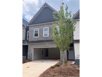 Two-story townhome with a brick facade, gray siding, a large two-car garage, and professional landscaping at 3106 Marbella Cir # 3, Kennesaw, GA 30152