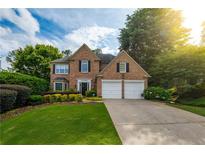 Charming brick home featuring a two-car garage, manicured lawn, and lush landscaping at 540 Shale Ct, Alpharetta, GA 30022