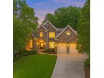 Charming two-story stone home with a manicured lawn and two-car garage at dusk at 5705 Registry Oaks Se Ln, Mableton, GA 30126