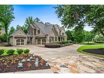 Beautiful brick home with a three-car garage, manicured landscaping, and a circular driveway at 771 Tate Overlook, Marietta, GA 30064