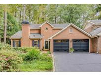 Charming brick home featuring a two-car garage, manicured front yard, and traditional architectural details at 2 Pointe Se Ter, Atlanta, GA 30339