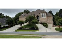 Elegant tan two-story home featuring a circular driveway and lush landscaping at 2503 Regency Lake Dr, Marietta, GA 30062