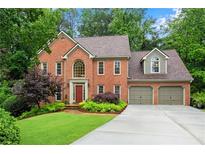 Lovely brick home with a well-manicured lawn, lush trees, and an attached two-car garage at 3915 Woolbridge Way, Marietta, GA 30062