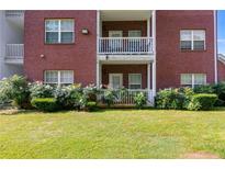 Brick apartment building with white balconies, complemented by a green lawn and flowering bushes at 7712 Autry Cir # 701, Douglasville, GA 30134