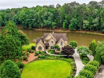 Beautiful two-story home with manicured lawn and lush landscaping overlooking a serene lake at 2675 Portabella Ln, Cumming, GA 30041