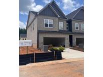 View of a gray brick two-story townhome featuring an attached garage and modern architectural details at 3108 Marbella Cir # 4, Kennesaw, GA 30152