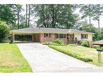 Charming brick ranch home with a long driveway and a covered carport nestled among mature trees at 2614 Princess Se Ln, Marietta, GA 30067