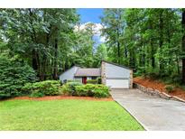 Charming home featuring a stone-accented facade, attached garage, and a lush, tree-filled landscape at 895 Fawn Way, Marietta, GA 30068