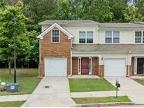 Inviting two-story townhome boasts brick accents, attached garage, and lush greenery at 5057 Lower Elm St, Atlanta, GA 30349