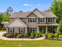Charming two-story home with a manicured front yard, lush landscaping, and inviting covered front porch with chairs at 13 Westbrook Rd, Carrollton, GA 30116
