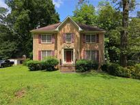 Traditional brick home featuring red shutters, a manicured lawn, and mature trees providing shade at 3692 Belmont Abbey Dr, Decatur, GA 30034