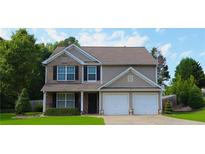 Charming two-story home featuring a brick and vinyl facade, well-manicured lawn, and a two-car garage at 4687 Riley Run Ct, Sugar Hill, GA 30518