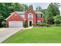 Charming two-story brick home with manicured lawn and attached two-car garage, surrounded by lush landscaping at 630 Beckenham Walk Dr, Dacula, GA 30019
