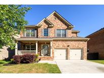 Charming two-story brick home with a well-manicured lawn, covered porch, and a two-car garage on a sunny day at 1021 Reddy Farm Rd, Grayson, GA 30017